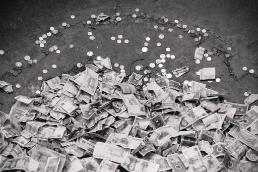 A grayscale shot of money bills and coins on the ground
