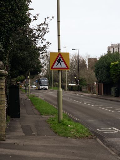 A vertical shot of a crossing road sign with Fareham council building and coach in the background