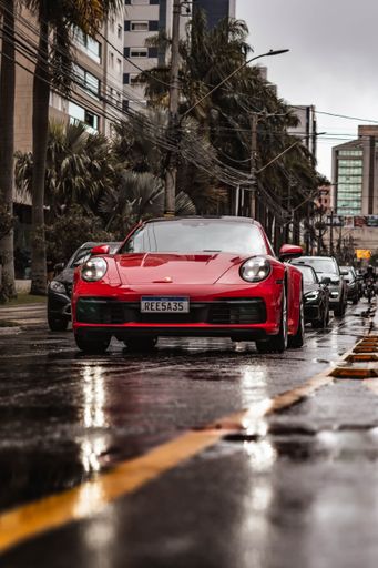 A Porsche 911 Carrera S in Carmin Red, front view in a rainy day setting