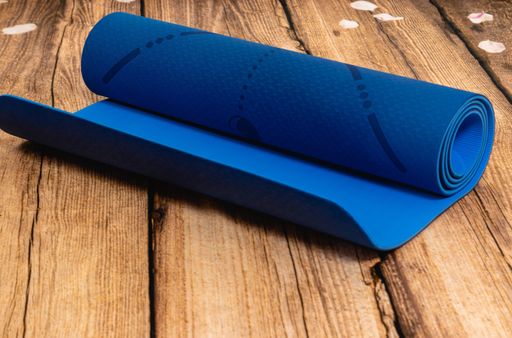 A closeup shot of a blue yoga mat on a wooden surface