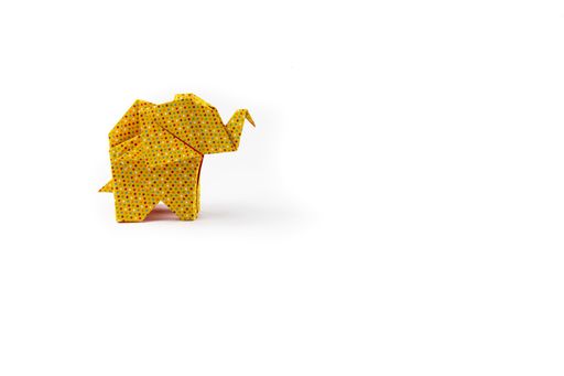 A closeup shot of a yellow patterned origami elephant isolated on a white background