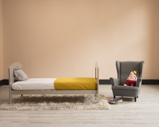 A wooden bed, an armchair and a toy in a child room