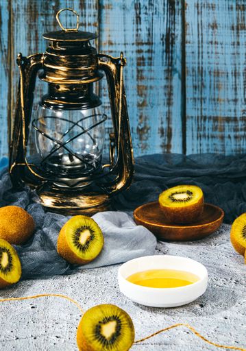 A vertical shot of a honey bowl and kiwis on background of a vintage lantern and grunge wall