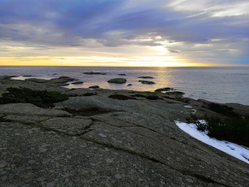 A sea surrounded by rocks under a cloudy sky during the sunset in Rakke in Norway