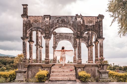 The woman in a white dress walks up the stairs of Taman Ujung palace ruins on Bali Island in Indonesia.
