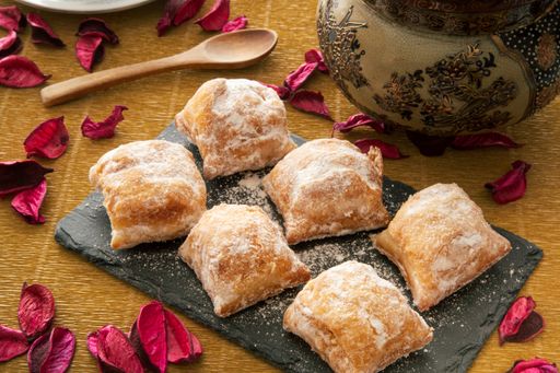 A high angle shot of freshly baked cakes with icing sugar on a black slate plate
