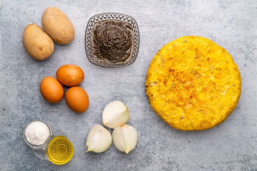 An overhead shot of ingredients and an omelet on a gray surface