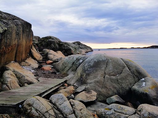 A sea surrounded by rocks under a cloudy sky during the sunset in Stavern in Norway