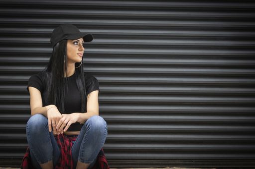 A young Hispanic woman in sporty clothes near a black wall