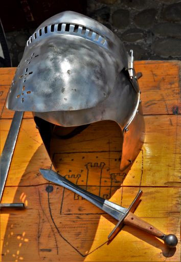 A vertical shot of medieval knight's armor and a sword on a wooden table