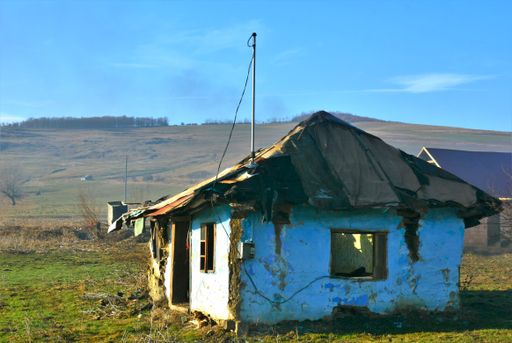A rustic shot of a ruined building on background of a mountain field in the village