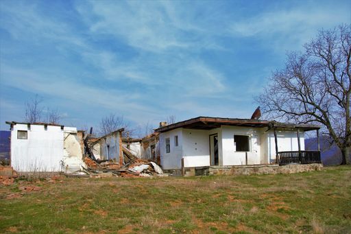 An old ruined house in a rural area under a cloudy sky
