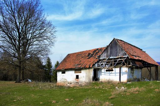 An old semi-destroyed abandoned rural house in nature on a sunny day