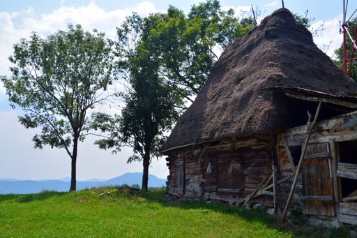 A closeup shot of an old Romanian traditional straw-roofed house under a clear blue sky