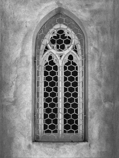 A grayscale of an arch window of a church with a metallic fence