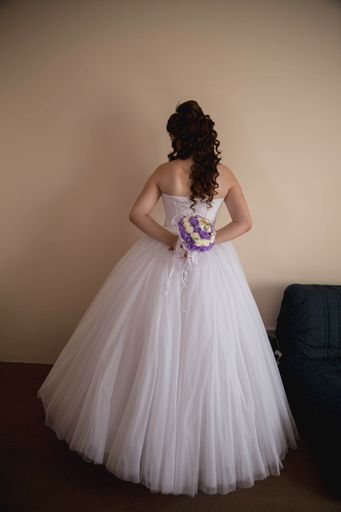 A vertical back view of a bride holding a bouquet