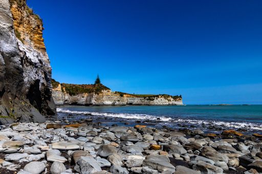 The black sand and stone beach in New Zealand during daylight