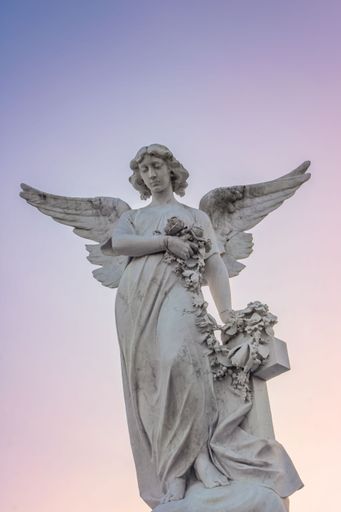 A statue stands tall in front of a beautiful sky, filled with vibrant hues of pink and orange at sunset