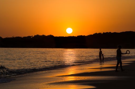 The crowded Praia de Nossa Senhora da Rocha beach in Lagoa, Algarve with people silhouettes at a beautiful sunset