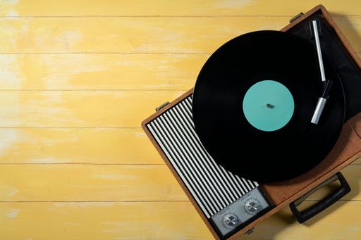 Old gramophone with a vinyl record on yellow wooden table
