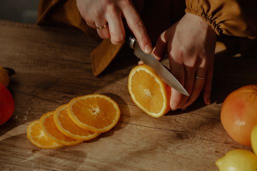 A person cutting oranges on a cutting board