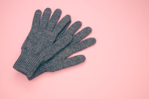 A closeup shot of wool blend gloves isolated on a pink background