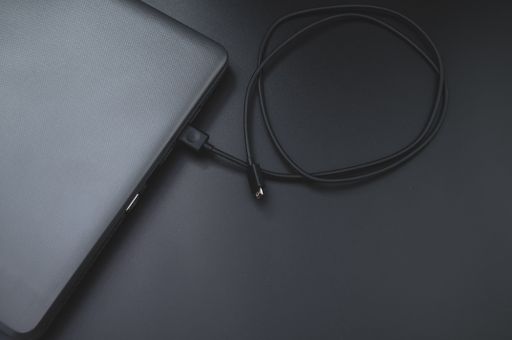 A top view of a laptop with a charging cable isolated on a black background