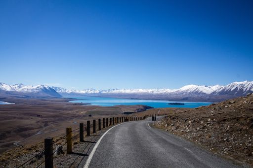Blue sky over Lake Tekapo, New Zealand with a street in the foreground and snowy mountains in the back