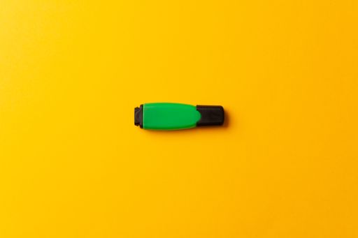 A top view of a green highlighter isolated on a yellow background