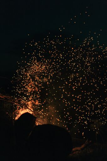 Burning hot sparks flying from the fire in the background of the night sky