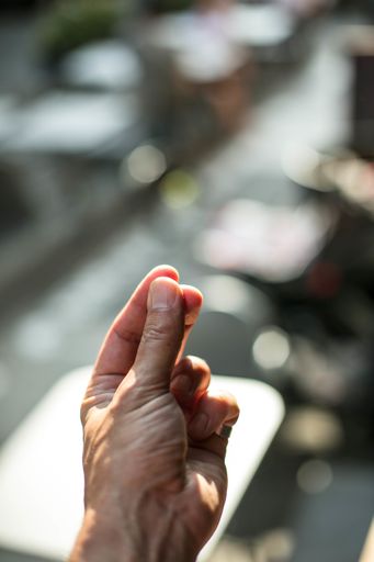 A vertical picture of snapping fingers under the lights with a blurry background and a bokeh effect