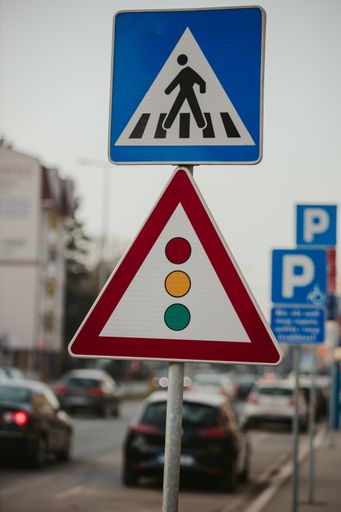 A shallow focus shot of a crossing and traffic light signs during daytime