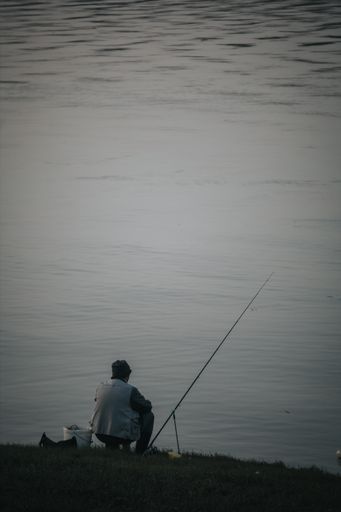 A vertical shot of a fisherman near the lake