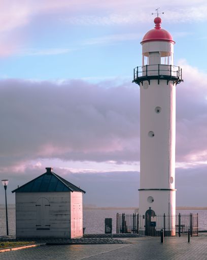 A lighthouse situated at the end of a pier surrounded by its iconic red roof
