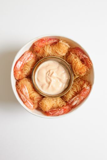 A top view of a cube of fried prawns wrapped in Kataifi pasta and served with dragon sauce