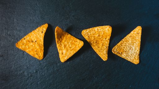 A closeup top view of triangle-shaped crunchy corn chips appetizer on a table surface