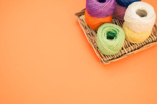 A high angle shot of colorful yarns on an orange surface under the lights