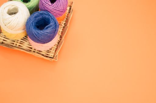 A high angle shot of colorful yarns on an orange surface under the lights