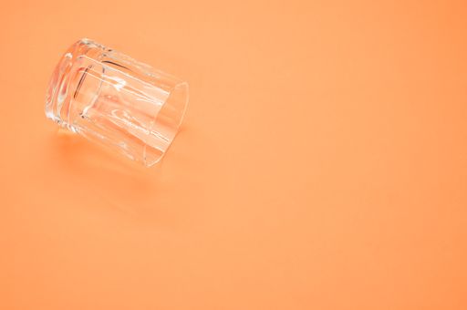 A f a shot glass under the lights isolated on an orange background