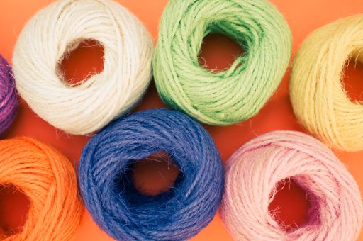 A closeup shot of colorful thread rolls on a orange surface
