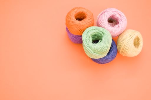 A high angle shot of colorful yarns on an orange surface under the lights