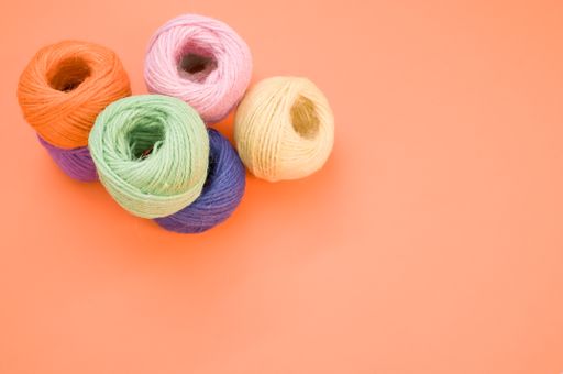 A top view of colorful yarns on an orange surface under the lights