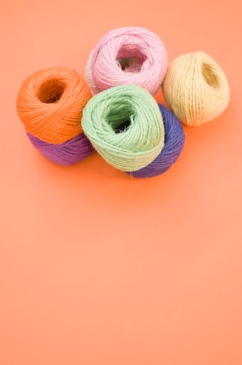 A vertical shot of colorful yarns on an orange surface under the lights