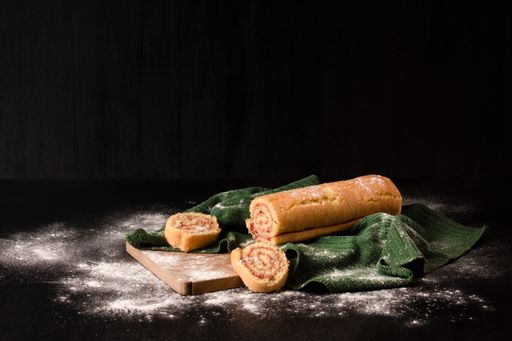 An appetizing homemade biscuit roll decorated with fresh berries on fabric textile with spilled flour