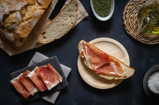 A top view of Serrano ham with bread and olive oil on the table with ingredients on it