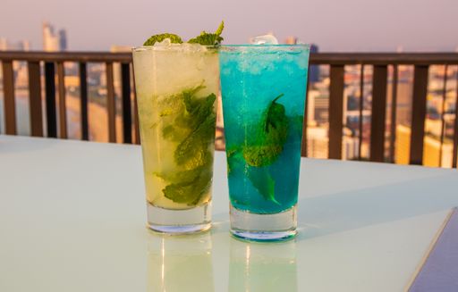 A closeup of two glasses of fresh mojito cocktails with ice cubes and mint leaves on the table