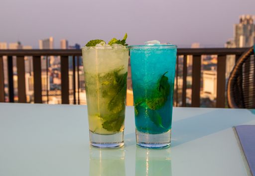 A closeup of two glasses of fresh mojito cocktails with ice cubes and mint leaves on the table
