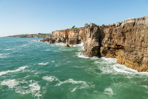 A landscape of the Boca do Inferno surrounded by the sea under a blue sky in Portugal