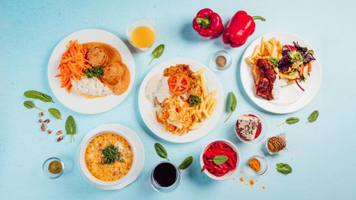 A top view of different dishes on a blue background with herbs around