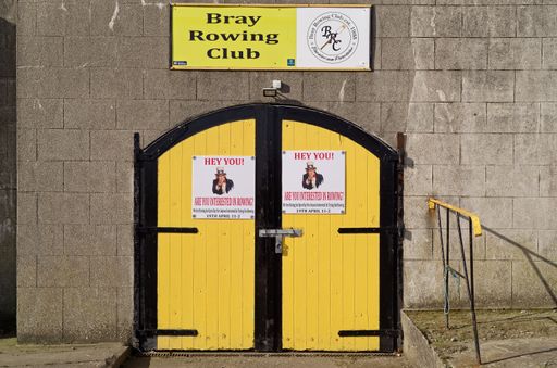 An entrance to the Bray Rowing Club in Bray town. Closed yellow wooden door with posters inviting to an open day in the club.
